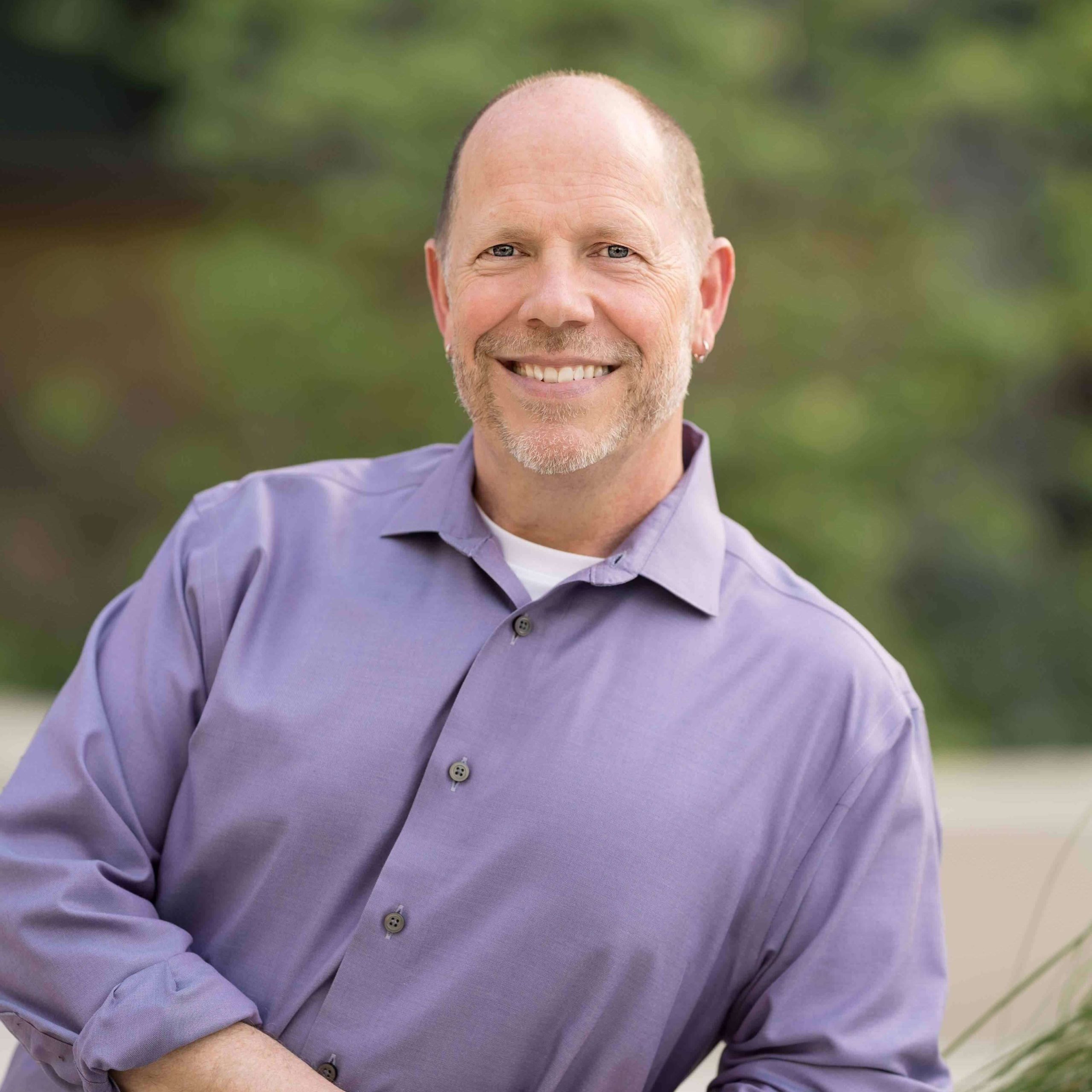 Paul Briley, life coach and consultant, smiling warmly at camera in light purple shirt